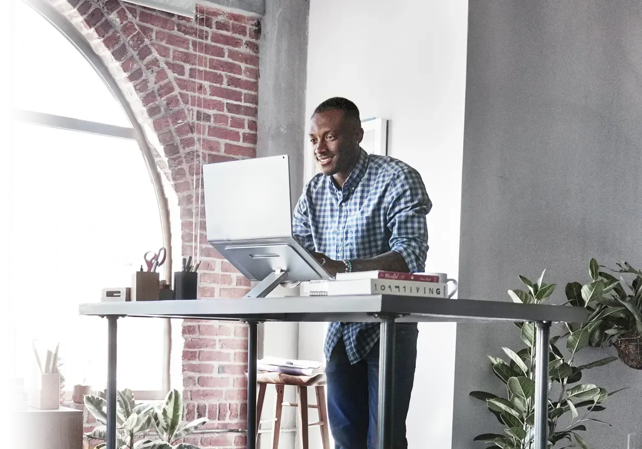 Man at a standing home office desk, and using laptop